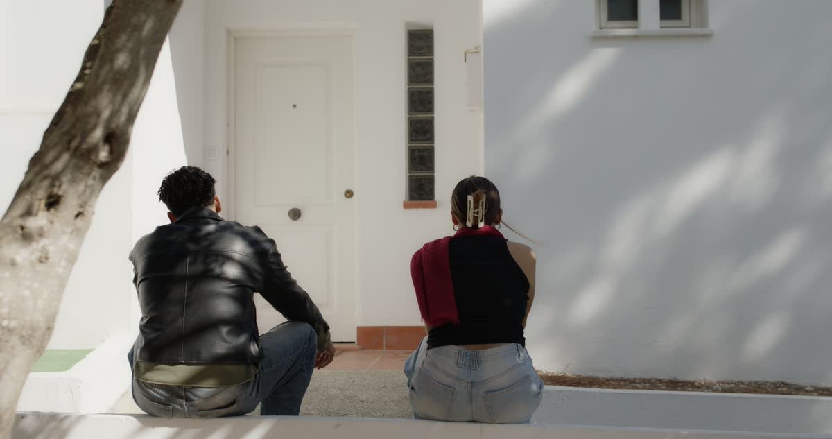 Clara y Adri sentados de espaldas frente a la puerta