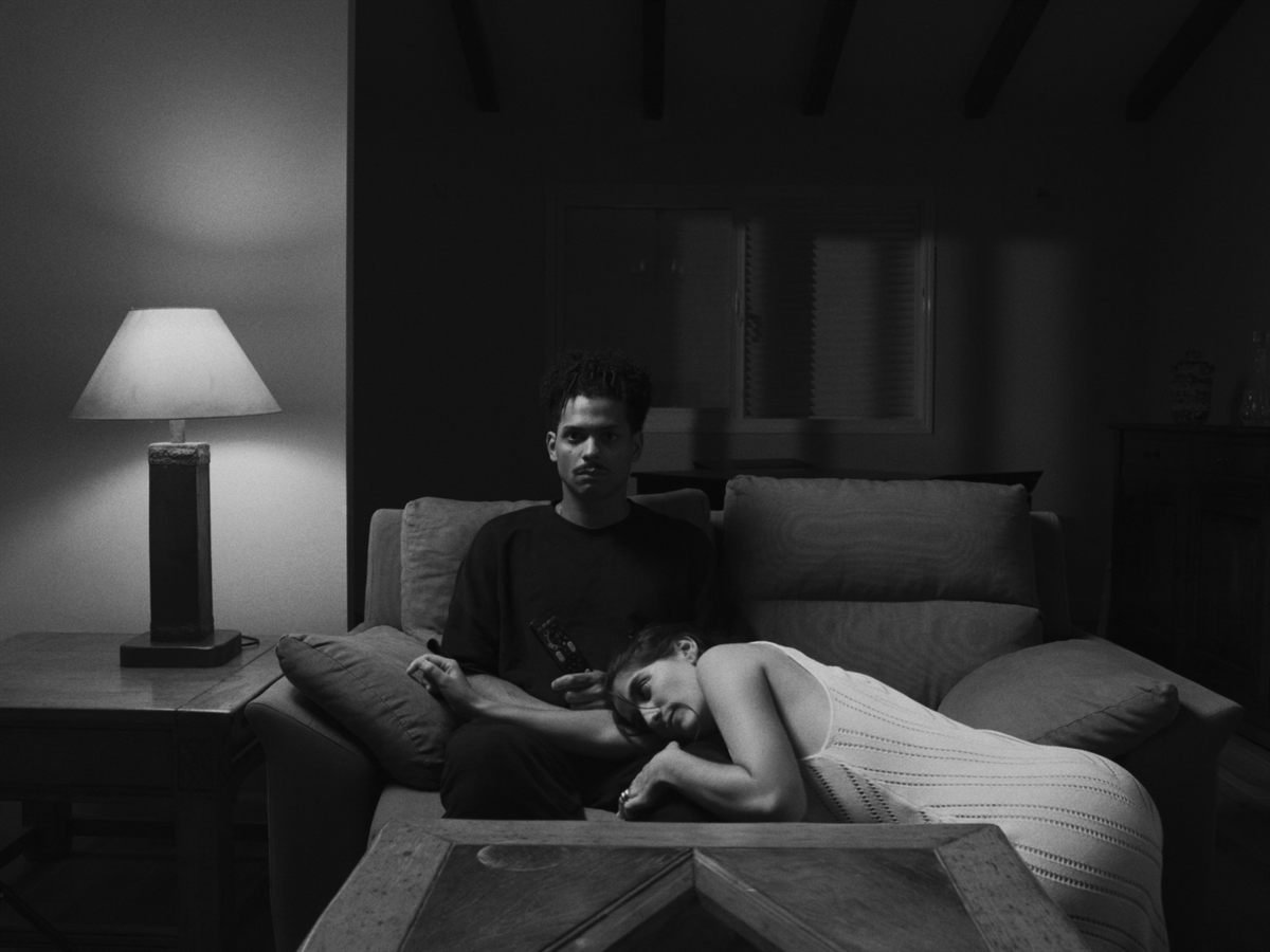 Personaje sentado en un sofá junto a una lámpara en blanco y negro
