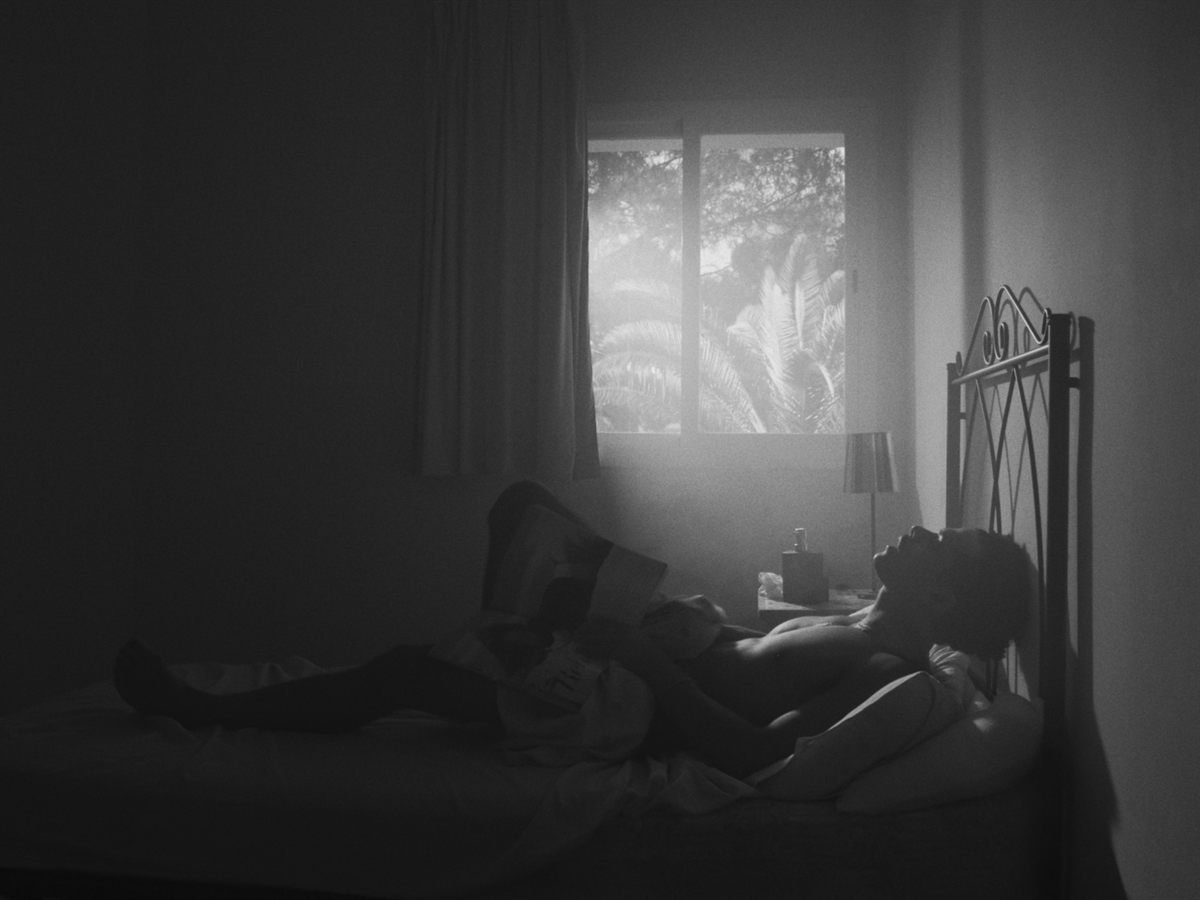 Personaje en una cama con luz de ventana en blanco y negro