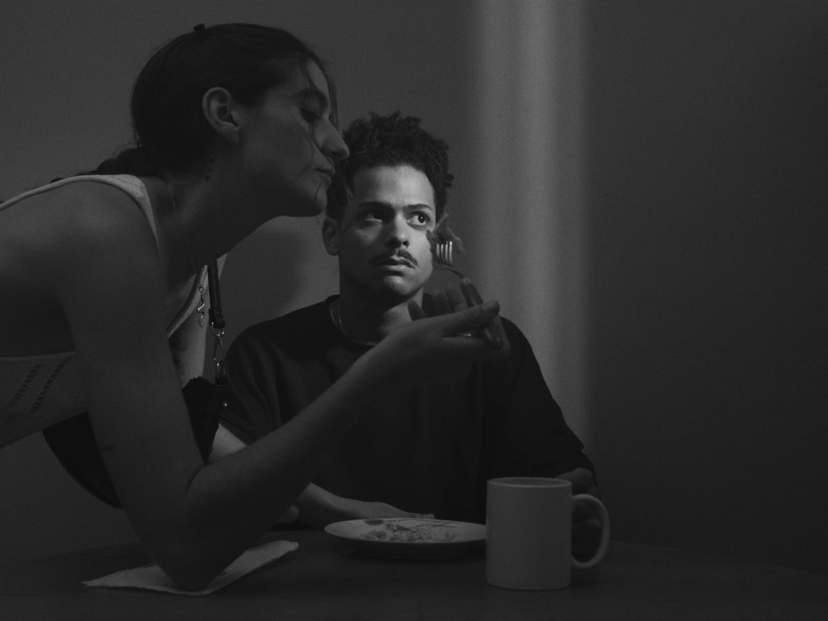 Dos personajes en una mesa con una taza en blanco y negro